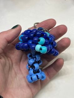 a hand holding a blue and black beaded key chain