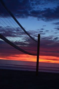 a beach volleyball net with the sun setting in the background