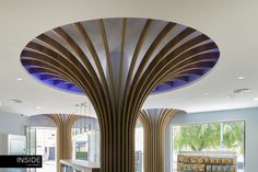 the interior of a modern restaurant with wood columns and circular lighting fixture in front of large windows