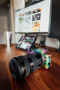 a camera sitting on top of a wooden table next to a computer monitor and tablet