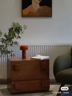 a painting hanging on the wall above a wooden dresser with a potted plant next to it