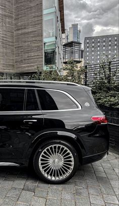 a black suv parked in front of a tall building on a cloudy day with buildings behind it