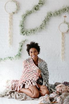 a woman sitting on the floor with some yarn