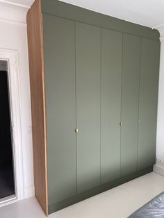 an empty room with green cabinets and a bed in the foreground, next to a sliding glass door