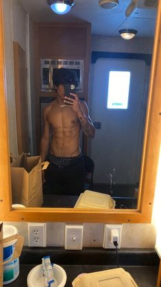 a shirtless man taking a selfie in front of a mirror with his cell phone