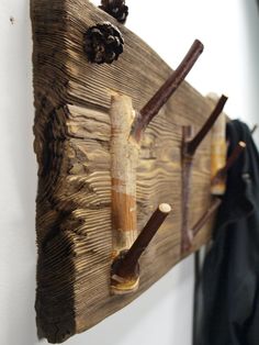 a coat rack made out of an old piece of wood and some pine cones hanging on the wall