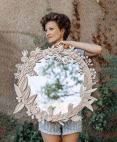 a woman holding up a mirror with flowers on it