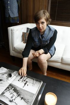 a woman sitting on a couch in front of a table with an old photo and candle