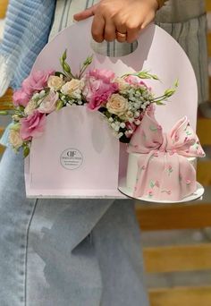 a person holding a pink gift bag with flowers on it