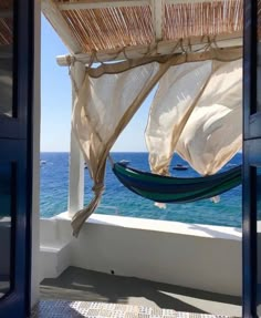 a hammock hanging from the side of a building next to an ocean view