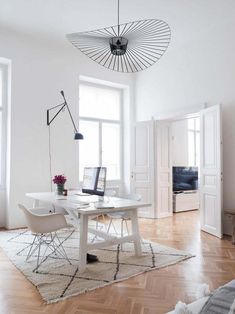 a white table and chairs in a room with wooden floors, windows, and rugs