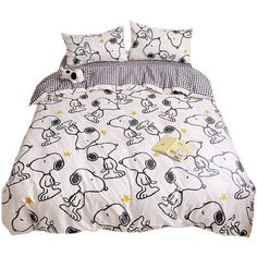 a white bed with black and white snoopy print on the comforter is shown