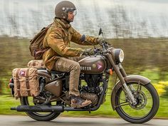 a man riding on the back of a brown motorcycle down a road with a backpack