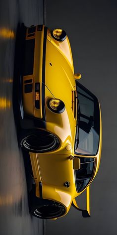 the front end of a yellow sports car with its lights on is seen from above