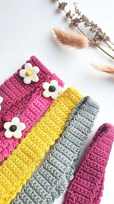 three crocheted headbands with flowers on them next to a dried flower