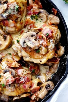 a skillet filled with chicken and mushrooms on top of a white cloth next to a fork