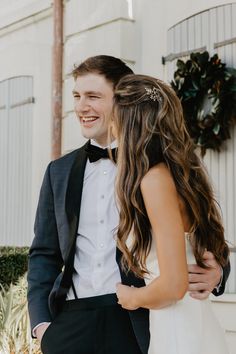 a man in a tuxedo is hugging a woman