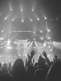 a group of people at a concert with their hands up in front of the crowd