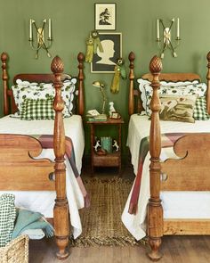 two beds in a room with green walls and wooden posts on the headboards,