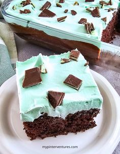 a piece of cake on a plate with mint frosting and chocolate pieces in the middle