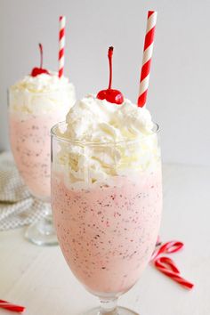 two glasses filled with ice cream and candy canes on top of a white table