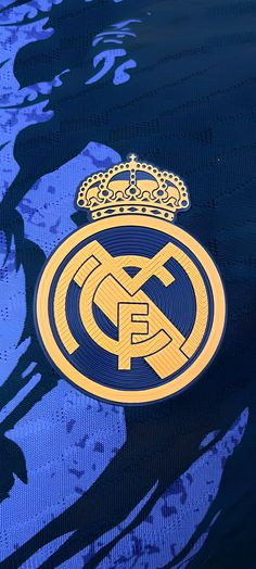 the real madrid crest is shown on a blue jersey with gold trims and a crown