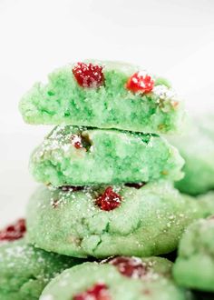 green cookies stacked on top of each other covered in powdered sugar and cherries