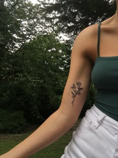 a woman with a flower tattoo on her left arm and right arm behind her back