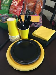 the table is set with black and yellow plates, napkins, cups, and other items