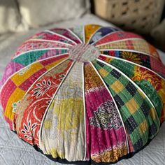 a multicolored round pillow on top of a bed