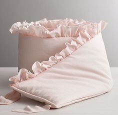 a pink pillow with ruffles on it sitting on top of a white table