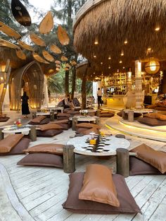 an outdoor lounge area with lots of pillows on the floor and palm trees in the background