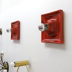 two red and one white light switch plates on the side of a wall in a room