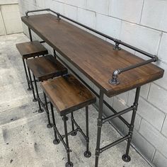 three stools are sitting next to each other near a brick wall with metal pipes on it