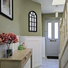 a vase with flowers sitting on a table in front of a door and some stairs