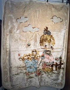 an old towel hanging on the wall with two people holding umbrellas and clouds in the sky