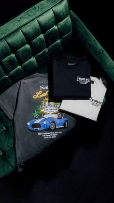 some t - shirts are laying on top of a green velvet chair with a black background