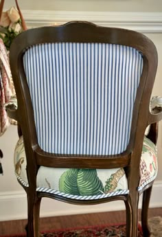 a blue and white striped chair sitting on top of a wooden floor next to a rug