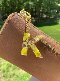 a person holding a brown purse with a yellow k on it