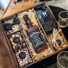 an assortment of liquor and nuts in a wooden box on top of a black table