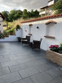 an outdoor patio with chairs and potted plants on the side of the building,