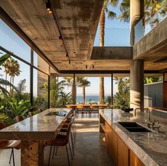 an open kitchen and dining area with palm trees in the background