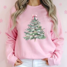 Celebrate the season with our charming Christmas Pink Bows Tree Sweatshirt, the perfect blend of festive cheer and cozy comfort. Embrace the holiday spirit in our Christmas Coquette Christmas Tree Sweater or the delightful Xmas Holiday Crewneck, each adorned with whimsical pink bows for a touch of seasonal elegance.    Deck your halls with a sprinkle of whimsy and a dash of pink magic! Our Christmas Pink Bows Tree Sweatshirt isn’t just apparel; it’s a declaration of festive flair and comfort. Imagine this vibrant, cozy piece glowing under your twinkling lights!  Picture yourself wrapped in the soft embrace of our Christmas Coquette Christmas Tree Sweater or the Xmas Holiday Crewneck. Each one is adorned with charming pink bows, turning your holiday wardrobe into a gallery of seasonal elega Casual Christmas Festive Sweatshirt, Casual Christmas Sweatshirt For Festive Occasion, Casual Christmas Sweatshirt, Cozy Crew Neck Top For Christmas, Christmas Cotton Sweatshirt, Festive Christmas Crew Neck Sweatshirt, Cute Winter Holiday Sweatshirt, Cute Holiday Crew Neck Sweatshirt, Cute Sweatshirt For Holiday Winter