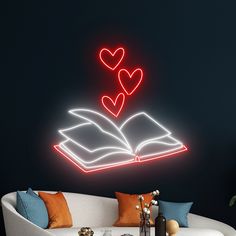 an open book with two hearts on the pages in front of a neon sign that reads love