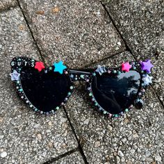 a pair of black sunglasses with stars on them sitting on the ground next to a sidewalk