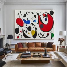 a living room filled with furniture and a large painting on the wall above it's fireplace