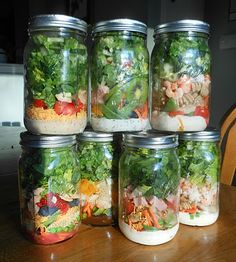 several mason jars filled with salads and dressing