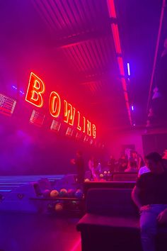 people are sitting at bowling tables with neon lights in the backgroung area