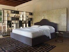 a large bed sitting in the middle of a bedroom next to a book shelf filled with books