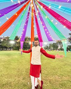 a man standing under a colorful umbrella in the grass